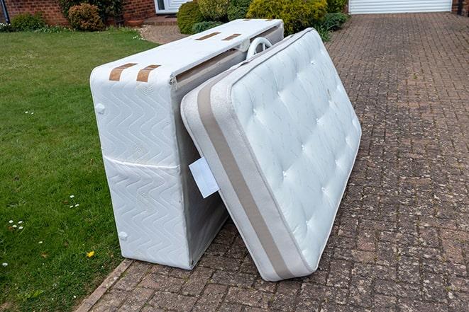 workers carrying old mattress out of a house